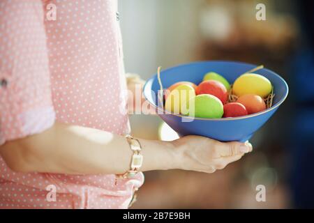 Closeup on woman holding a blue plate with colorful easter eggs at home in sunny spring day. Stock Photo