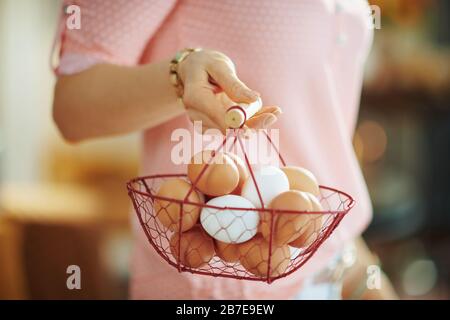 Closeup on housewife holding basket with eggs for coloring at home in sunny spring day. Stock Photo