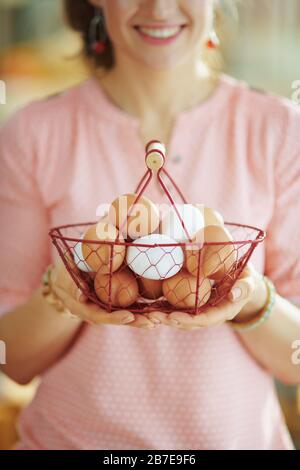 Closeup on female holding basket with eggs at home in sunny spring day. Stock Photo