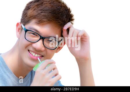 Closeup face Asian handsome teenage boy wearing glasses drinking water from straw in plastic cup, Portrait cheerful hipster young man are smiling with Stock Photo