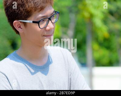 Asian handsome teenage boy wearing glasses and thoughtful gestures, Portrait cheerful hipster young man pursed lips and looking with a suspicious face Stock Photo