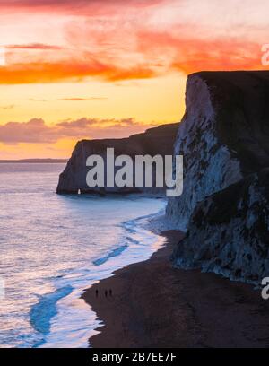 Durdle Door, Lulworth, Dorset, UK.  15th March 2020.  UK Weather.  A spectacular fiery sunset at Durdle Door on the Dorset Jurassic Coast near Lulworth looking towards Swyre Head and Bats Head as the cloud clears as high pressure builds in from the South West.  Picture Credit: Graham Hunt/Alamy Live News Stock Photo