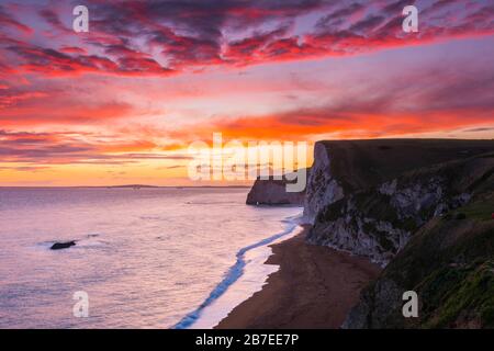 Durdle Door, Lulworth, Dorset, UK.  15th March 2020.  UK Weather.  A spectacular fiery sunset at Durdle Door on the Dorset Jurassic Coast near Lulworth looking towards Swyre Head and Bats Head as the cloud clears as high pressure builds in from the South West.  Picture Credit: Graham Hunt/Alamy Live News
