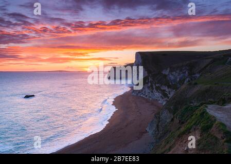 Durdle Door, Lulworth, Dorset, UK.  15th March 2020.  UK Weather.  A spectacular fiery sunset at Durdle Door on the Dorset Jurassic Coast near Lulworth looking towards Swyre Head and Bats Head as the cloud clears as high pressure builds in from the South West.  Picture Credit: Graham Hunt/Alamy Live News Stock Photo