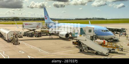 BRISTOL AIRPORT, ENGLAND - AUGUST 2019: Panoramic view of a TUI Boeing 737 holiday jet surrounded by ground equipment at Bristol Airport. Stock Photo