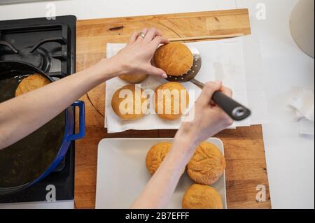 Top view of a woman placing freshly baked home made vegan doughnuts on a paper towel. Stock Photo