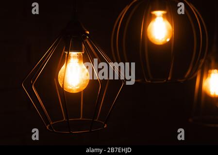 Close-up of an incandescent lamp. Light bulb with orange light. Burning an incandescent edison lamp with a large decorative spiral. Stock Photo