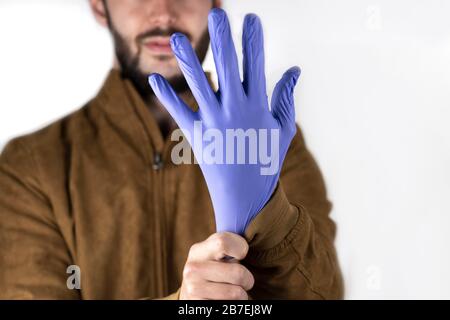 Young man putting on a blue latex glove. Commercial tone photo focused on the world of cleaning or medicine. Stock Photo