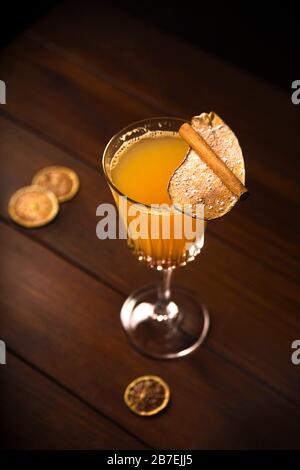 A glass of white mulled wine with a pear sprinkled with icing sugar on a dark background. Hot alcoholic drink in moody style. Stock Photo