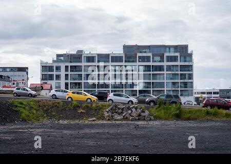Old apartment building with cars parked in front on a cloudy day Stock Photo