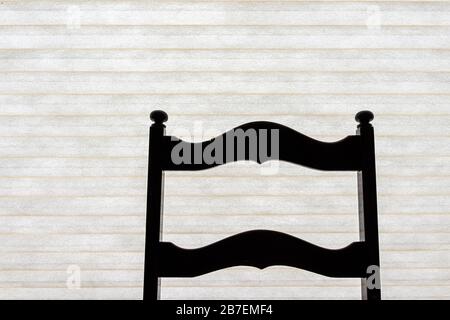 Dark chair silhouette in minimalism house interior and white curtain wall blinds in background in bedroom office or dining room Stock Photo