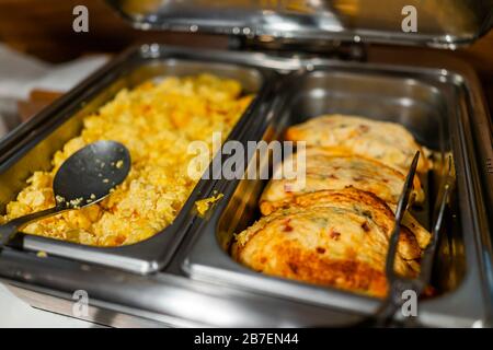 Fresh hot buffet tray with spoon to serve food scrambled eggs omelette in banquet, wedding, or restaurant inside for morning continental breakfast in Stock Photo