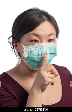 young asiatic woman wearing a green protection mask with medical gloves making shut up sign on a white background Stock Photo