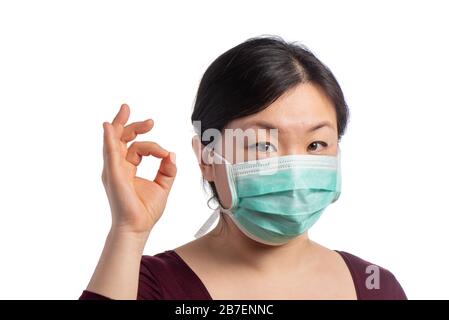 young asiatic woman wearing a green protection mask with medical gloves making ok sign on a white background Stock Photo