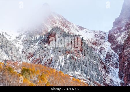 Maroon Bells red elk mountains view in Aspen, Colorado USA with rocky mountain and snow in autumn with winter mist fog cloud covering peak closeup Stock Photo