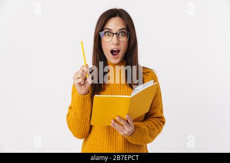 Image of beautiful brunette adult woman wearing eyeglasses making notes in diary book isolated over white background Stock Photo