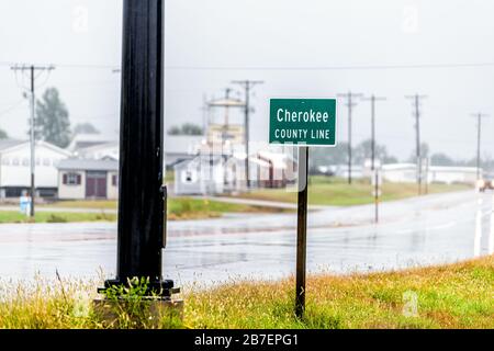 Chetopa, USA rainy street road in small town in Kansas countryside with sign for Cherokee county line by houses Stock Photo