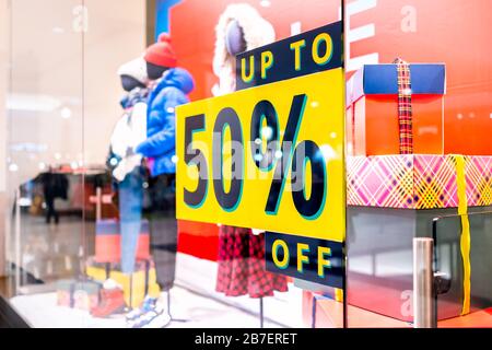 Up to 50% off price reduction promotion sign on window display at clothes clothing store or apparel winter shop in Europe with mannequins Stock Photo