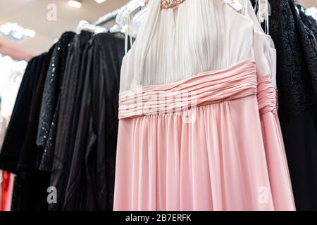 European style white and pink formal female woman dress hanging on clothes hanger in apparel store shop boutique in Europe Stock Photo