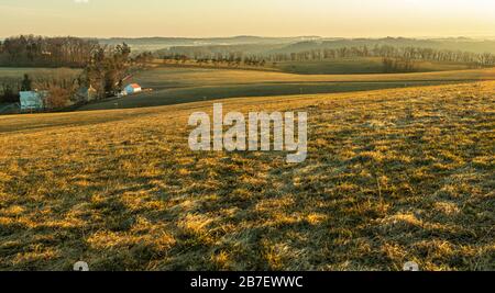 Warm sunrise on hill overlooking fields. Stock Photo