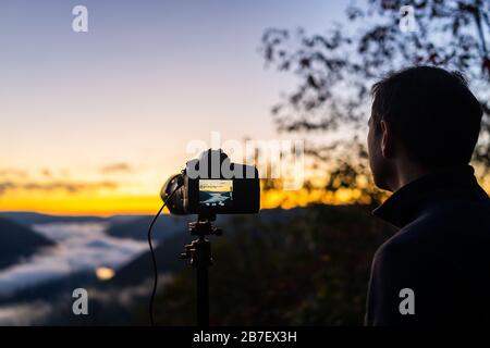 Fog mist cloud inversion on mountains with man doing timelapse in morning at new river gorge valley in Grandview Overlook, West Virginia during mornin Stock Photo