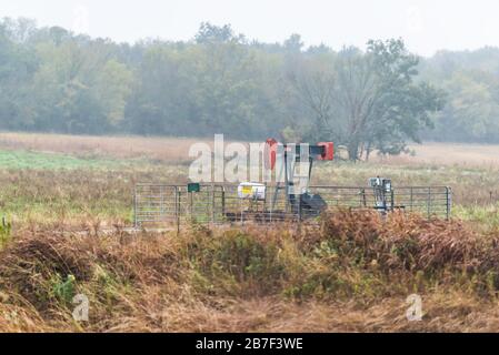 Wichita, USA - October 15, 2019: View of oil jack pump in Kansas industrial countryside on misty cloudy day in agricultural farm field Stock Photo