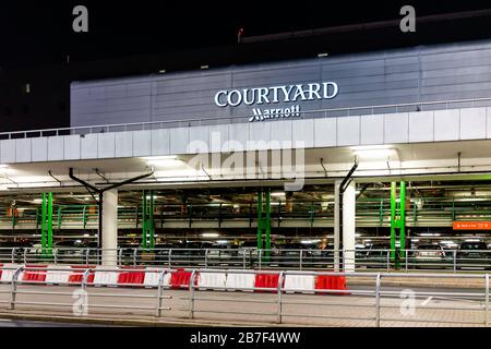 Warsaw, Poland - December 17, 2019: Courtyard by Marriott hotel building in Chopin international airport at night with parking lot and cars at rental