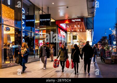 Warsaw, Poland - December 19, 2019: TK Max discount outlet store sign entrance with people walking on Marszalkowska street sidewalk at night with Chri Stock Photo