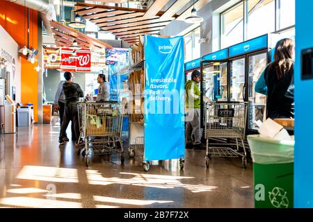 Ashburn, USA - February 2, 2020: Whole Foods interior in Virginia with prime now fresh delivery and employess stocking bags with produce by blue sign Stock Photo