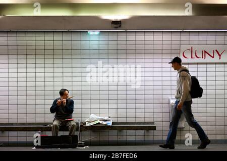 A man walks by a busker performing in the Cluny La Sornbonne Metro station, Left Bank, Paris, France, Europe, color Stock Photo