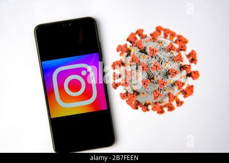 Stone / United Kingdom - March 15 2020: Instagram logo on smartphone and blurred Coronavirus image on the blurred background. Stock Photo