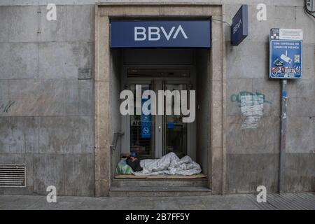 Madrid, Spain. 15th Mar, 2020. A homeless person sleeping at the door of closed BBVA bank during the corona virus lock down.Due to the state of emergency decreed by the Spanish government following the COVID-19 threat, the streets and viewpoints of the cities are empty. Credit: SOPA Images Limited/Alamy Live News Stock Photo