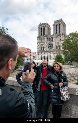 Tourists posing for a picture in front of the Notre Dame cathedral in Paris, France, Europe Stock Photo