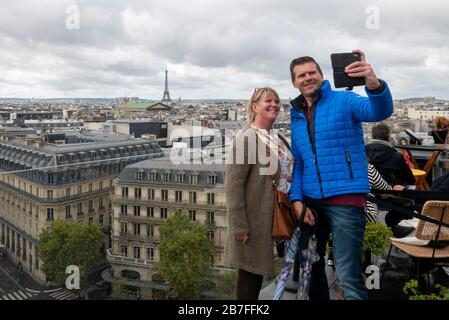 Two people taking a selfie together from the rooftop of the Galleries Lafayette with the Eiffel Tower in the background, Paris, France, Europe Stock Photo
