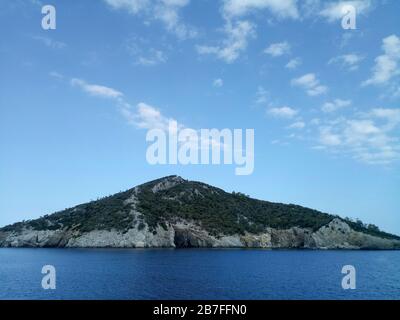 Kelyfos island between Sithonia and Kassandra near Neos Marmaras with blue sky filled with small clouds. Stock Photo