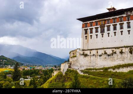 Rinpung Dzong above the Paro Chu river valley and town buildings on a cloudy day in Paro, Bhutan Stock Photo
