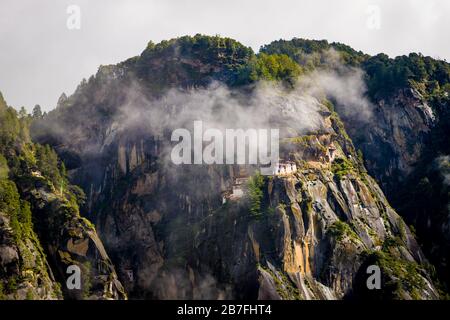 Paro Taktsang (Tiger's Nest) Monastery on a cliff face behind some mist near Paro, Bhutan Stock Photo