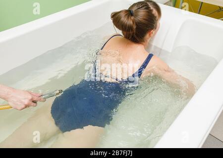 Woman in bath during hydromassage in beauty spa salon. Underwater hydrotherapy massage procedure Stock Photo