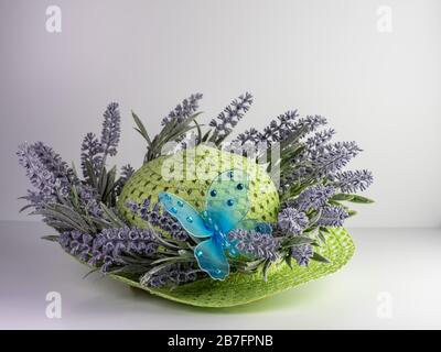 Green straw hat decorated with purple lavender and a blue butterfly with gem stones, for spring or Easter, on a white background.  Fashion accessory! Stock Photo