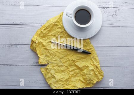 yellow crumpled paper , pen and tea on table  Stock Photo
