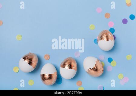 Cute light blue background with gilded eggs and confetti. Stock Photo