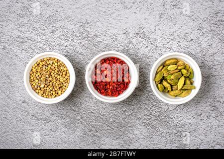 mix of aromatic spices coriander, bergamot, paprika in white cups on a gray concrete background Top view Flat lay Healthy food. Stock Photo