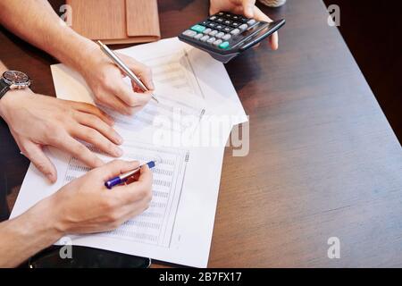 Business people discussing figures in financial report at meeting and making calculations Stock Photo