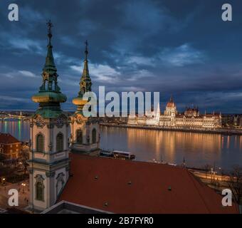 Budapest, Hungary - Aerial view of the Saint Anne Parish Church at Batthyany Square at dusk with illuminated Hungarian Parliament building at backgrou Stock Photo
