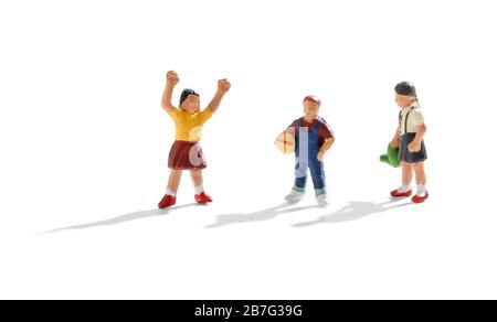 Three young miniature kids playing together with two little girls and a boy playing with a ball over a white background with shadow and copy space Stock Photo