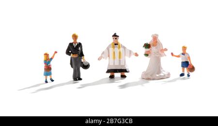 Complete wedding group of miniature people with priest standing between the bride and groom and a young flowergirl and page boy over white Stock Photo
