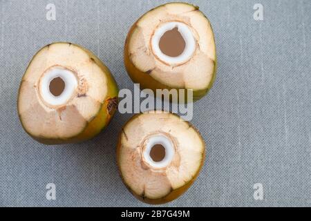 Three green coconuts with holes for straw stand on a gray surface, flat lay, top view photo Stock Photo