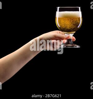 Woman hand holding lager beer glass isolated on black. Stock Photo