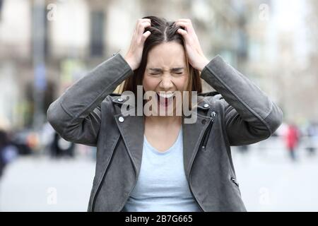 Front view portrait of anxious desperate woman screaming on city street Stock Photo