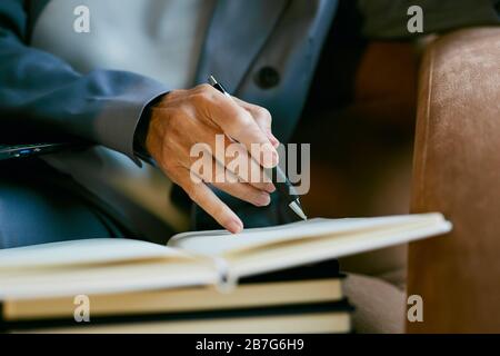 Close up of mature successful businesswoman holding pen while taking notes in planner, copy space Stock Photo